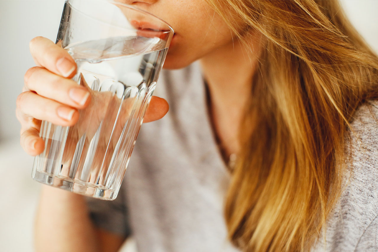 Nainen juo vettä lasista