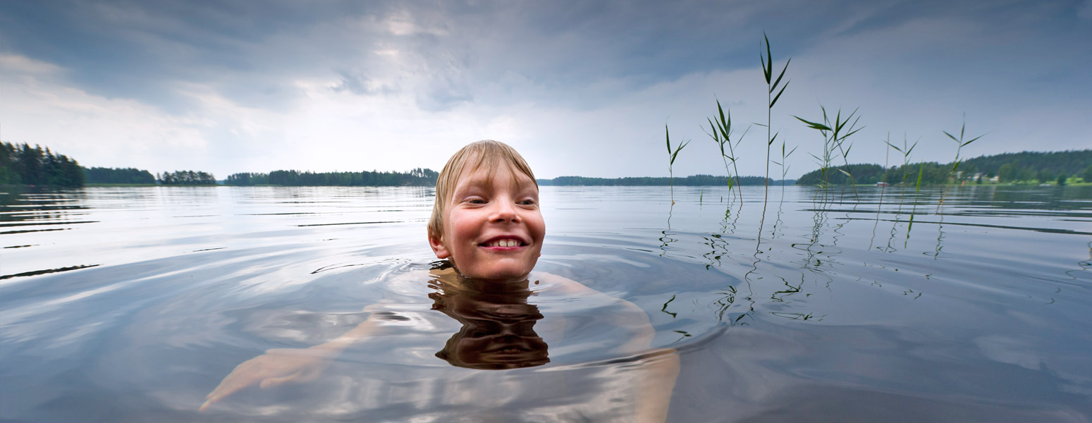 Nuori iloinen poika ui järvessä.