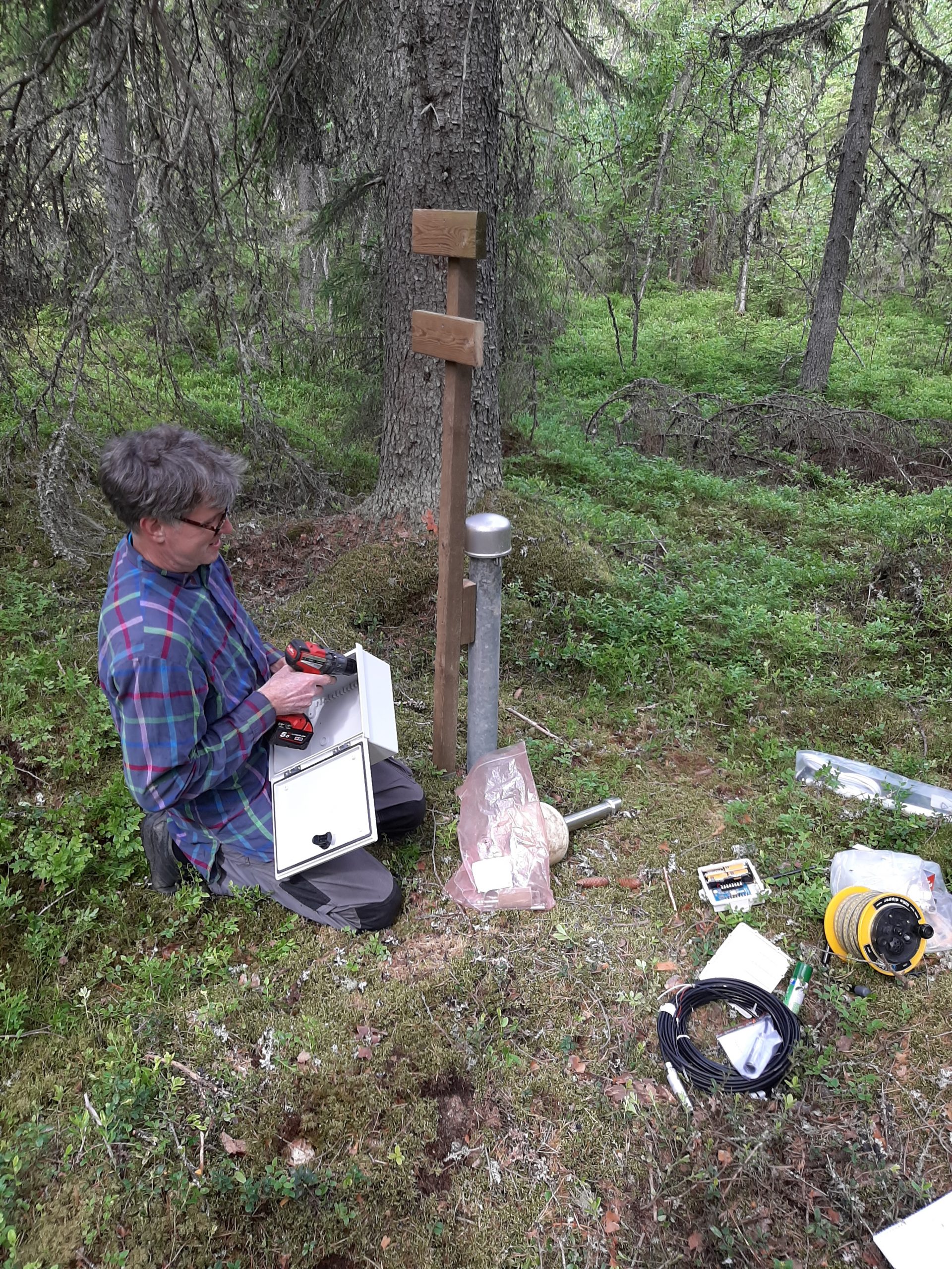 Mies metsässä pohjavesimittalaitteiden ja työkalujen kanssa.